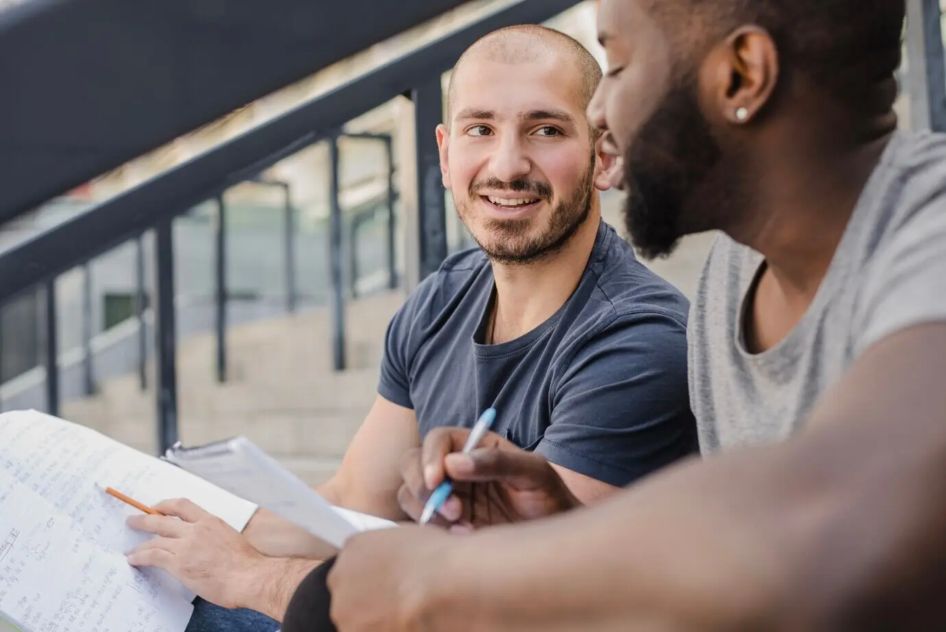 Zwei Studenten mit Papieren, die miteinander kommunizieren.